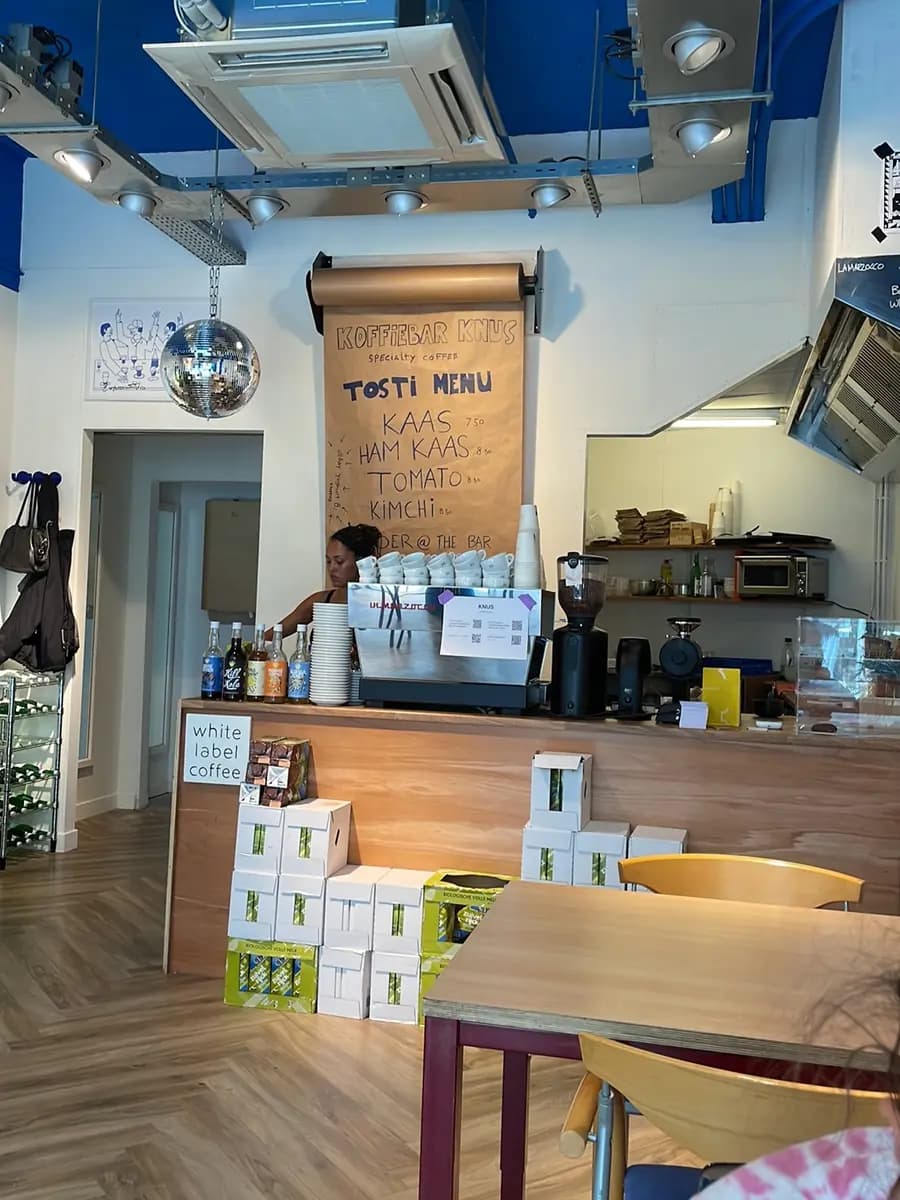 De toonbank met de handgeschreven tostikaart op bruin papier en de espressomachine erachter.